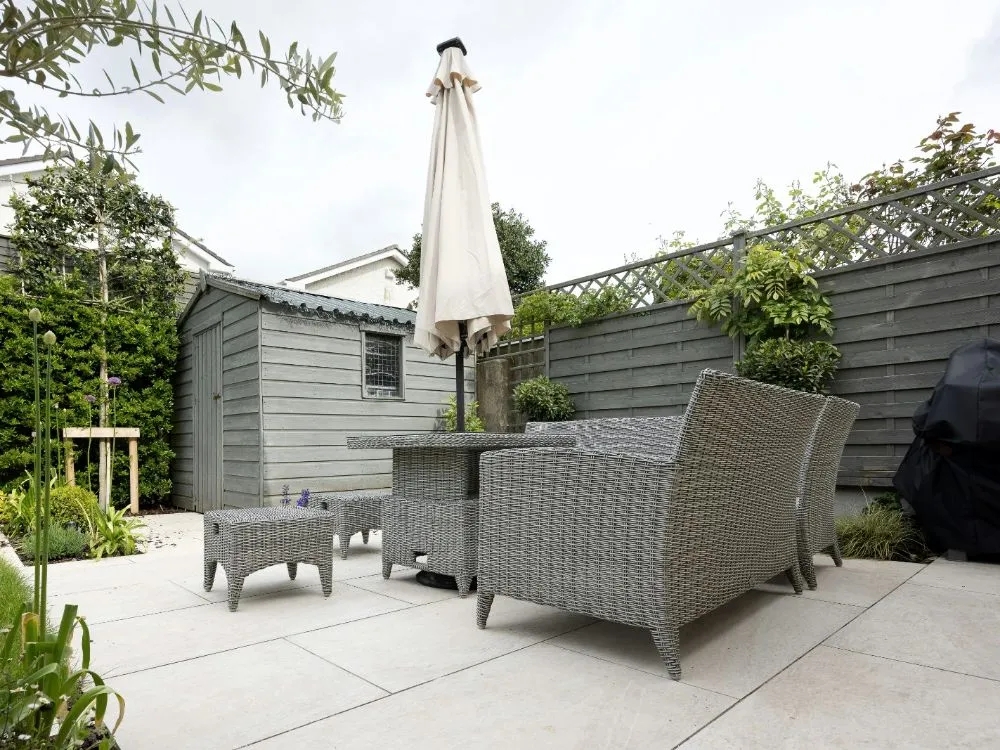 Backyard concrete patio with outdoor furniture and an umbrella