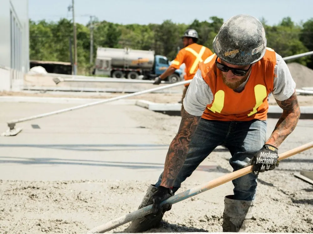 Concrete worker raking fresh concrete into place