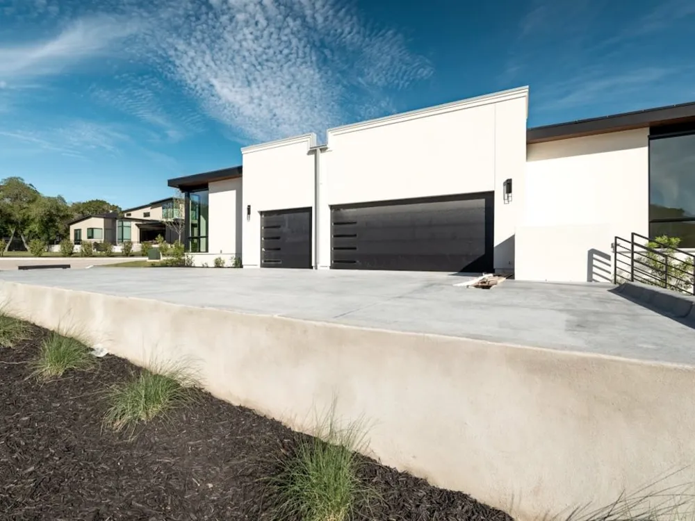 Wide new concrete driveway leading up to a two-car garage